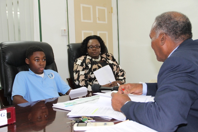 Premier of Nevis Hon. Vance Amory interacts with Jayden Dore, a student of the Nevis International Secondary School at his Bath Hotel office on April 19, 2016, after Jayden’s presentation of a desalination proposal for Nevis, while Junior Minister of Youth and Sports Hon. Hazel Brandy-Williams looks on